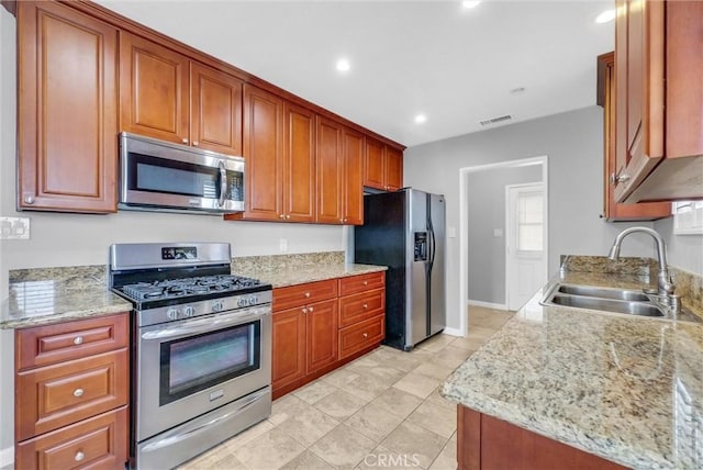 kitchen featuring light stone counters, recessed lighting, visible vents, appliances with stainless steel finishes, and a sink