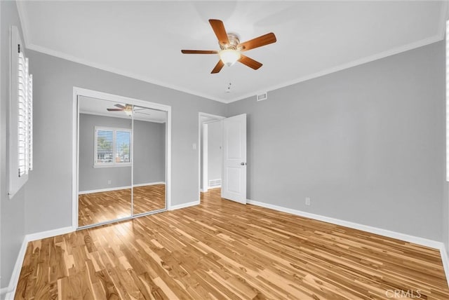 unfurnished bedroom with crown molding, ceiling fan, wood-type flooring, and a closet