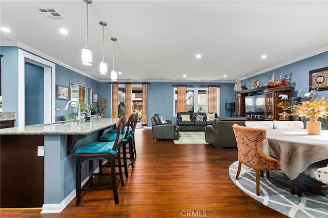 kitchen featuring sink, light stone counters, hanging light fixtures, a center island with sink, and dark hardwood / wood-style flooring