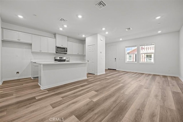 kitchen featuring a kitchen island with sink, white cabinetry, and stainless steel appliances