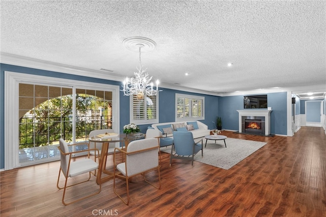 dining space with crown molding, wood-type flooring, a textured ceiling, and a healthy amount of sunlight