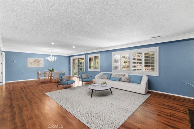 living room featuring ornamental molding, hardwood / wood-style floors, a textured ceiling, and an inviting chandelier