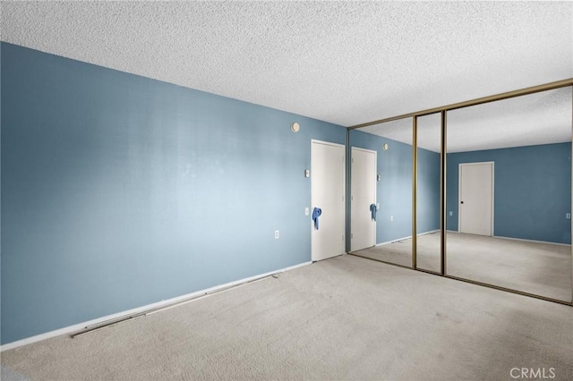 unfurnished bedroom with a textured ceiling, carpet floors, and a closet