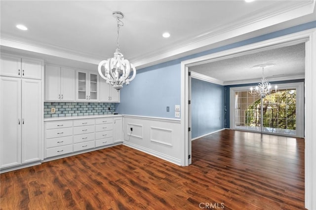 kitchen featuring a chandelier, white cabinets, light countertops, glass insert cabinets, and crown molding