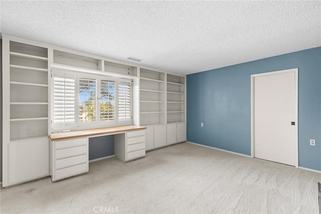 interior space featuring carpet, visible vents, built in desk, and a textured ceiling