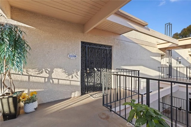 entrance to property featuring a balcony and stucco siding