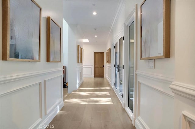 hallway featuring crown molding and light hardwood / wood-style floors