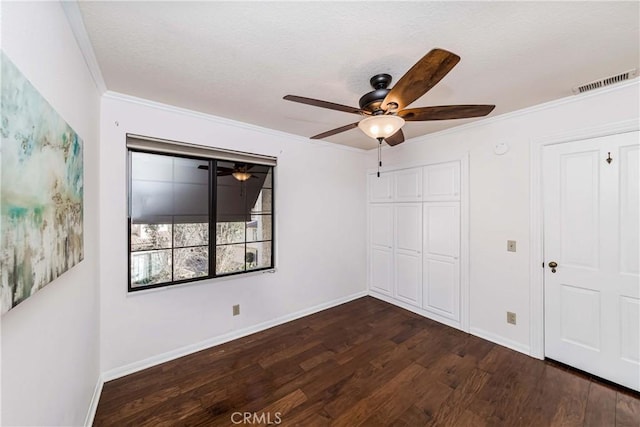 unfurnished bedroom with dark hardwood / wood-style flooring, crown molding, a closet, and ceiling fan