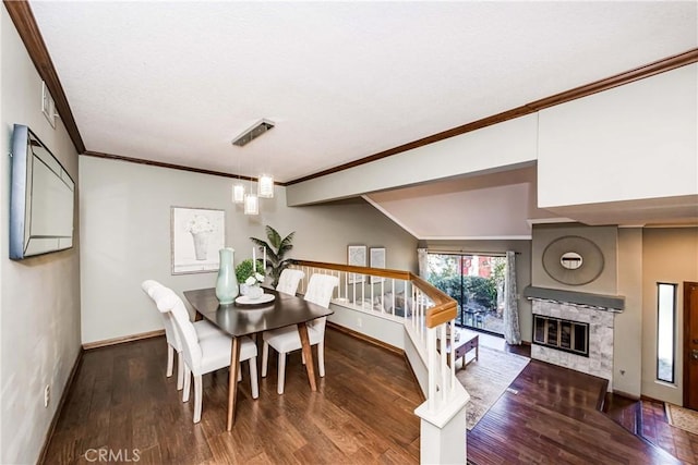 dining space featuring a tile fireplace, dark wood-type flooring, and crown molding