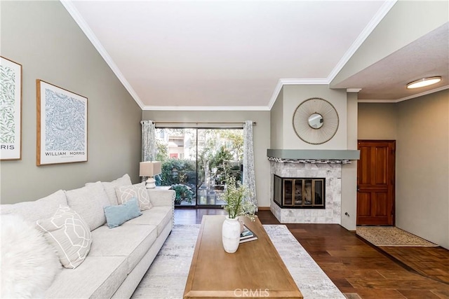 living room with a tiled fireplace, hardwood / wood-style floors, crown molding, and vaulted ceiling