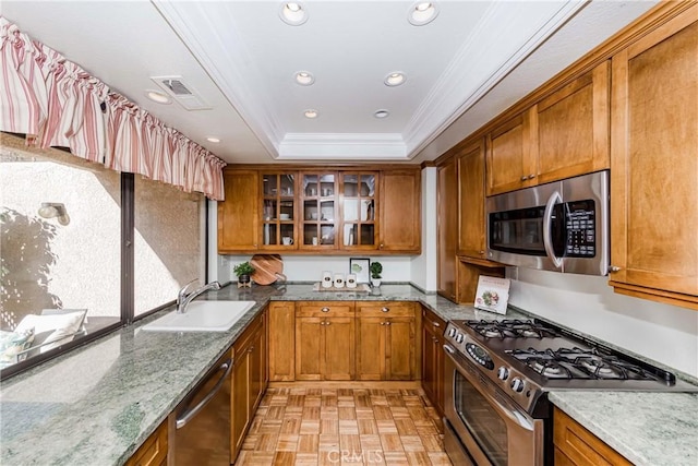 kitchen with stainless steel appliances, sink, crown molding, a tray ceiling, and light parquet flooring