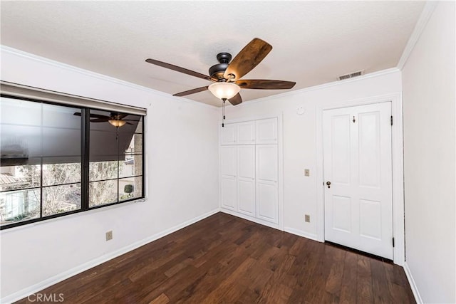 unfurnished bedroom with crown molding, dark hardwood / wood-style floors, a closet, and ceiling fan