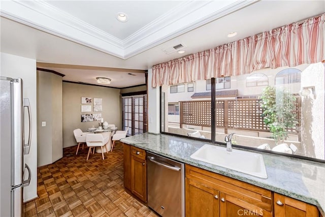 kitchen with sink, parquet floors, light stone counters, stainless steel appliances, and crown molding