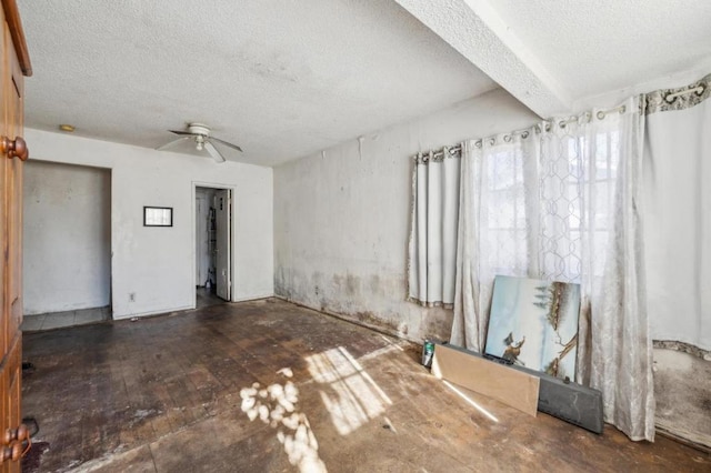 empty room featuring ceiling fan, dark wood-type flooring, and a textured ceiling