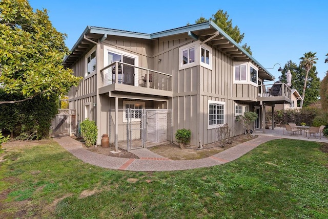 rear view of house with a balcony, a yard, and a patio area