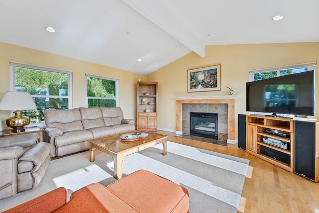 living room featuring lofted ceiling with beams, a fireplace, and light hardwood / wood-style floors