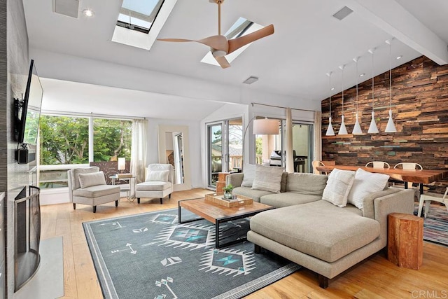 living room with a healthy amount of sunlight, vaulted ceiling with skylight, and light hardwood / wood-style flooring