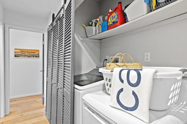 laundry room with independent washer and dryer, a barn door, and light wood-type flooring