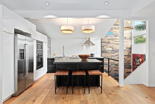 kitchen featuring white cabinetry, decorative light fixtures, a kitchen island, stainless steel appliances, and backsplash