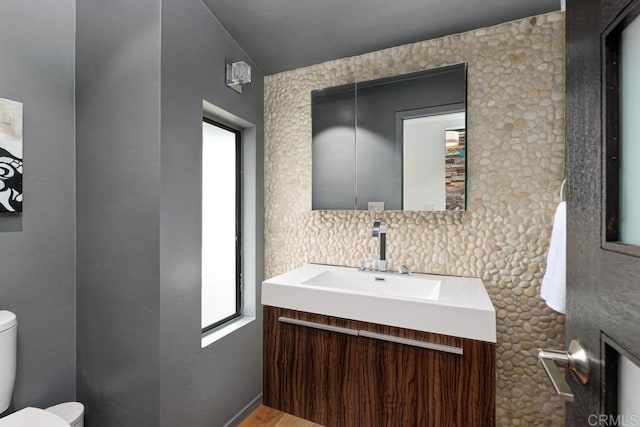 bathroom with vanity, plenty of natural light, backsplash, and toilet