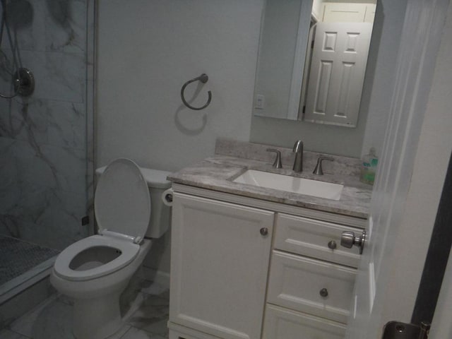 bathroom featuring vanity, toilet, and a tile shower