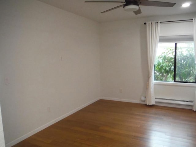 empty room with hardwood / wood-style flooring, a baseboard radiator, and ceiling fan