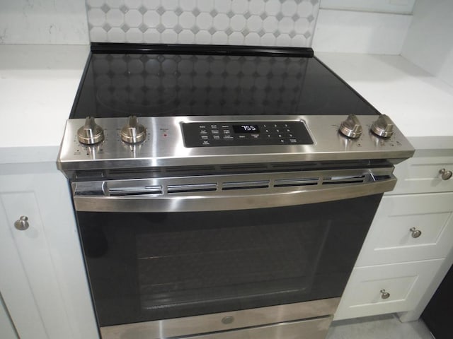 details with wall oven, decorative backsplash, and white cabinets