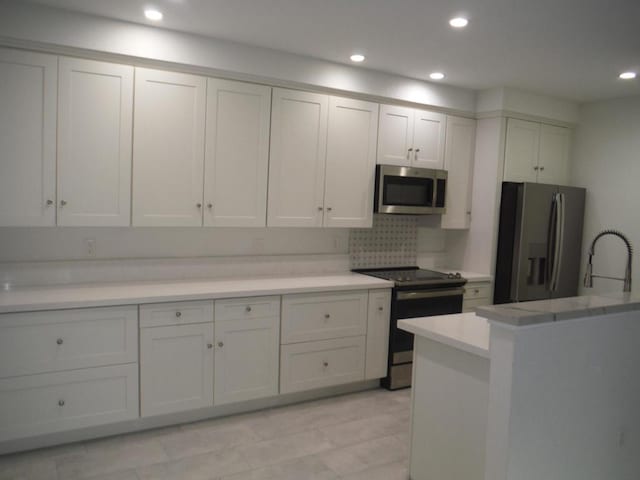 kitchen featuring white cabinetry, appliances with stainless steel finishes, and backsplash