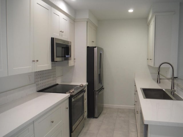 kitchen with stainless steel appliances, sink, white cabinets, and backsplash