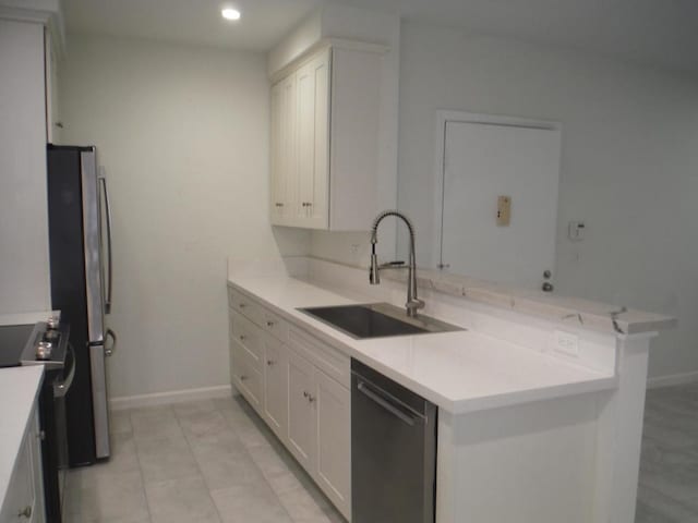 kitchen with sink, light tile patterned floors, appliances with stainless steel finishes, white cabinetry, and kitchen peninsula