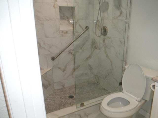 bathroom featuring toilet and a tile shower