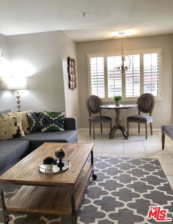 living room with a wealth of natural light, light tile patterned floors, and an inviting chandelier