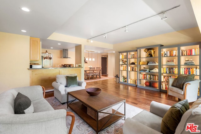 living room featuring built in shelves, track lighting, and light hardwood / wood-style flooring