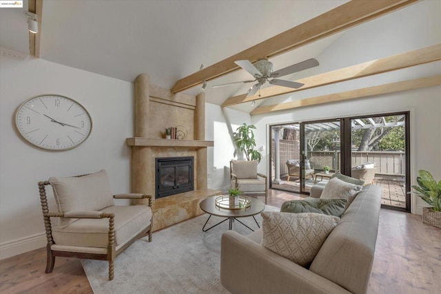 living room featuring ceiling fan, a high end fireplace, light wood-type flooring, and vaulted ceiling with beams