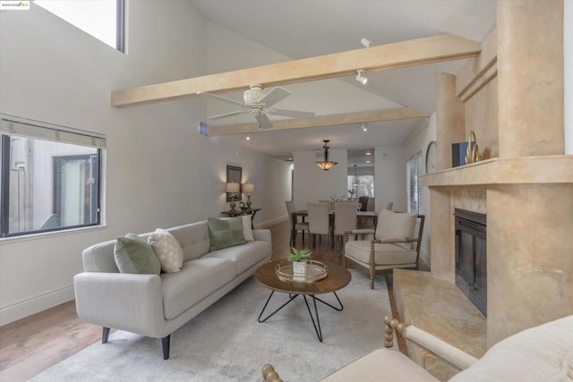 living room with high vaulted ceiling, light wood-type flooring, beamed ceiling, ceiling fan, and a high end fireplace