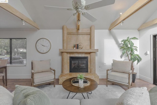 living room with rail lighting, lofted ceiling with beams, ceiling fan, a high end fireplace, and light hardwood / wood-style floors