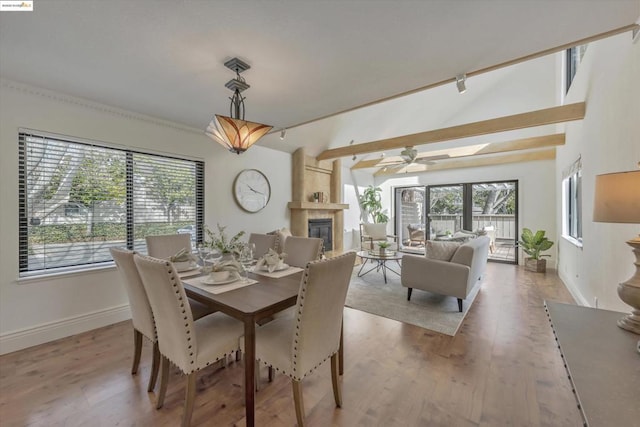 dining room featuring a fireplace, vaulted ceiling, wood-type flooring, and ceiling fan