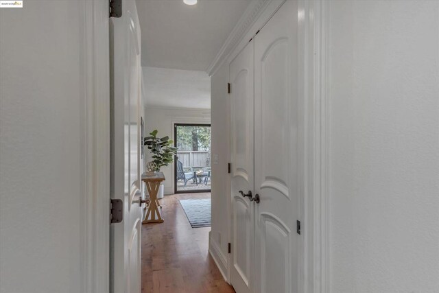 hallway with ornamental molding and light hardwood / wood-style flooring