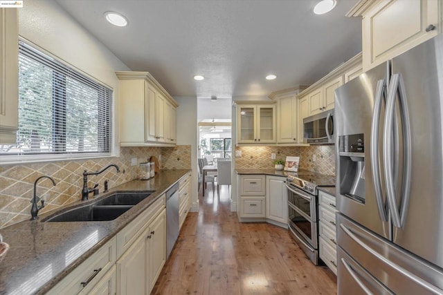 kitchen featuring cream cabinets, appliances with stainless steel finishes, sink, and dark stone counters