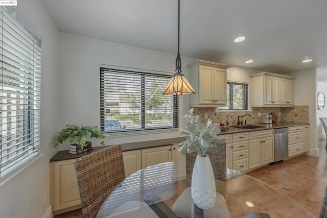 kitchen featuring sink, decorative light fixtures, stainless steel dishwasher, cream cabinets, and decorative backsplash