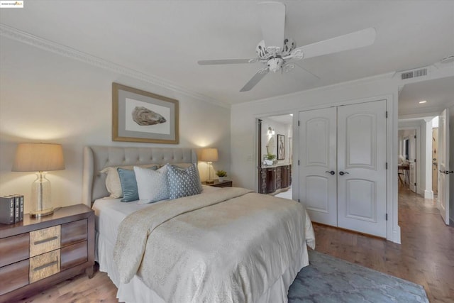 bedroom with a closet, ornamental molding, light hardwood / wood-style floors, and ensuite bathroom