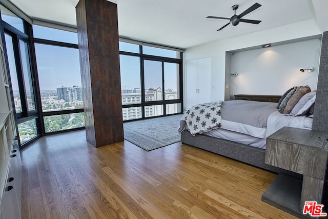 living room with hardwood / wood-style flooring, a wall of windows, and ceiling fan