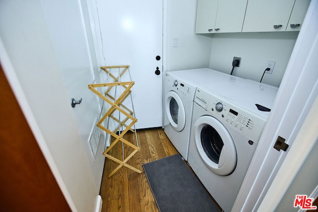 laundry area with cabinets, washing machine and dryer, and dark hardwood / wood-style flooring