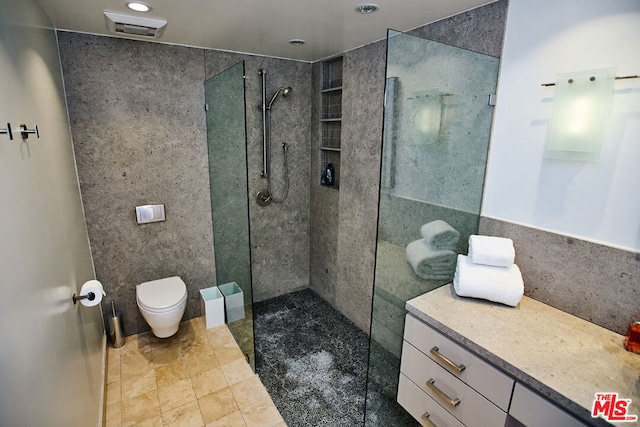 bathroom featuring vanity, a tile shower, and toilet