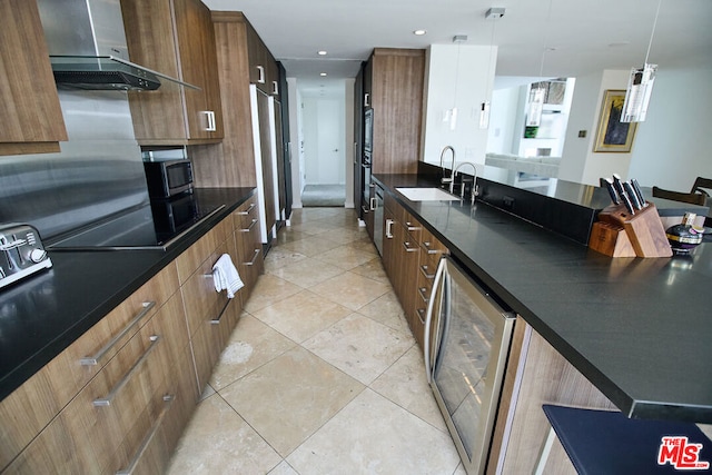 kitchen featuring sink, black electric cooktop, pendant lighting, beverage cooler, and wall chimney range hood