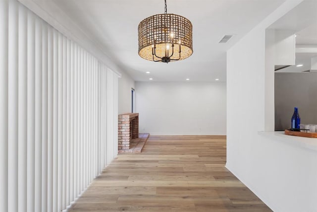 hall with light hardwood / wood-style flooring and a notable chandelier