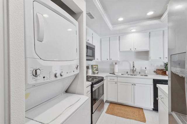 kitchen with sink, light tile patterned floors, stacked washer and dryer, white cabinetry, and stainless steel appliances