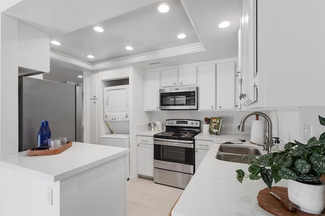 kitchen with sink, white cabinetry, appliances with stainless steel finishes, a raised ceiling, and stacked washing maching and dryer