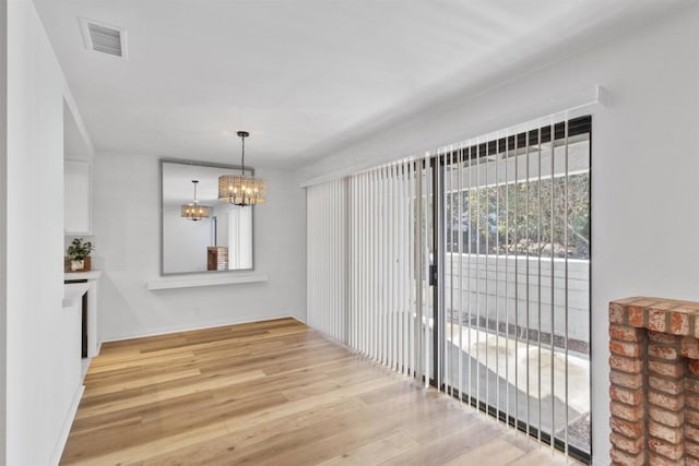 unfurnished dining area with a notable chandelier and light hardwood / wood-style flooring