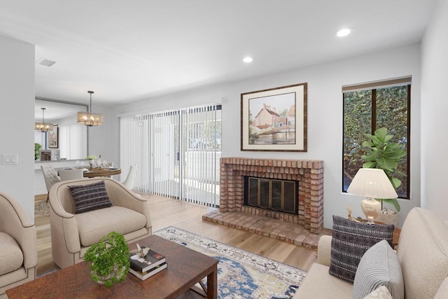 living room with a notable chandelier, hardwood / wood-style flooring, a wealth of natural light, and a fireplace